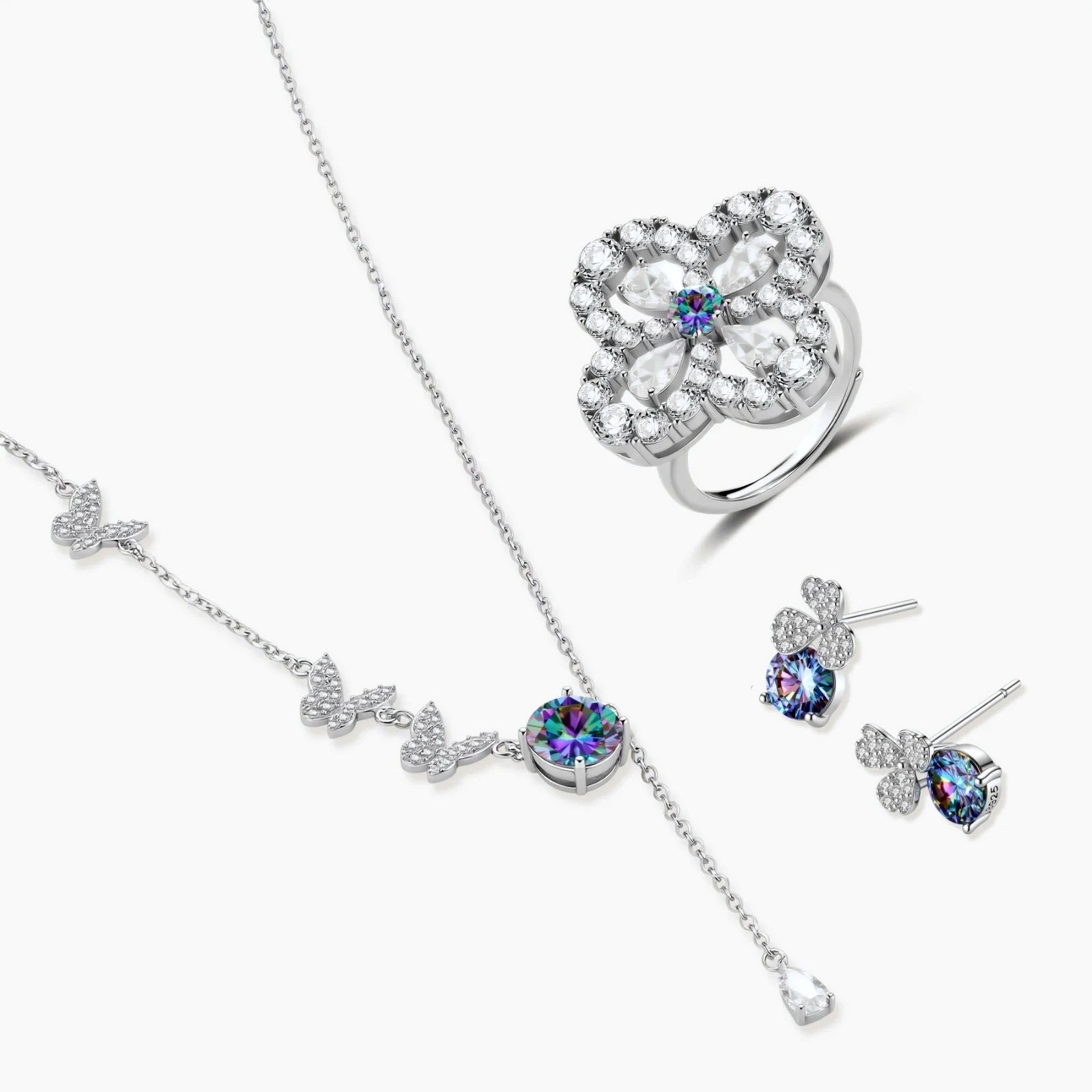 Sterling silver jewelry set with rainbow moissanite stones in clover and butterfly designs on cream background