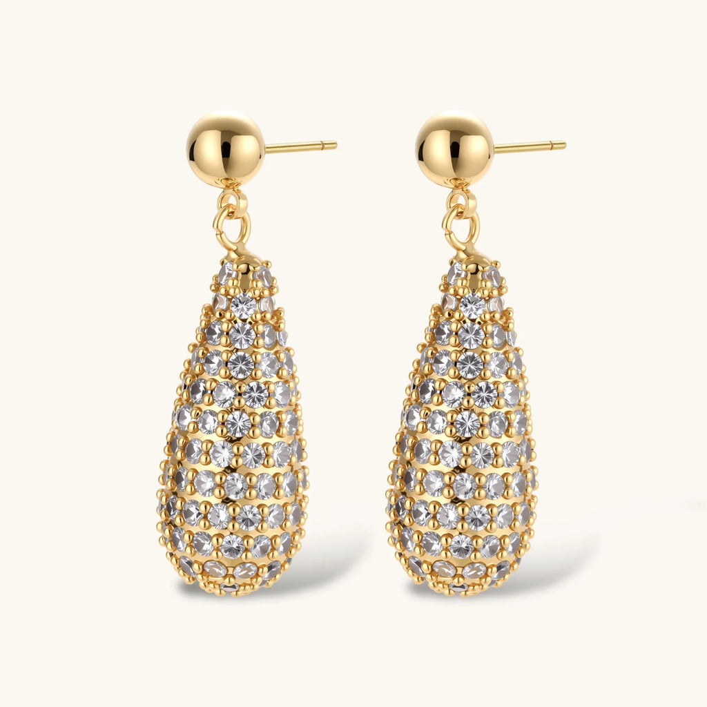 Gold-plated teardrop necklace and earrings covered in AAA cubic zirconia crystals on cream background.