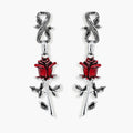 Gothic dangle earrings featuring silver serpent hooks with red enamel roses and metallic stems on white background.