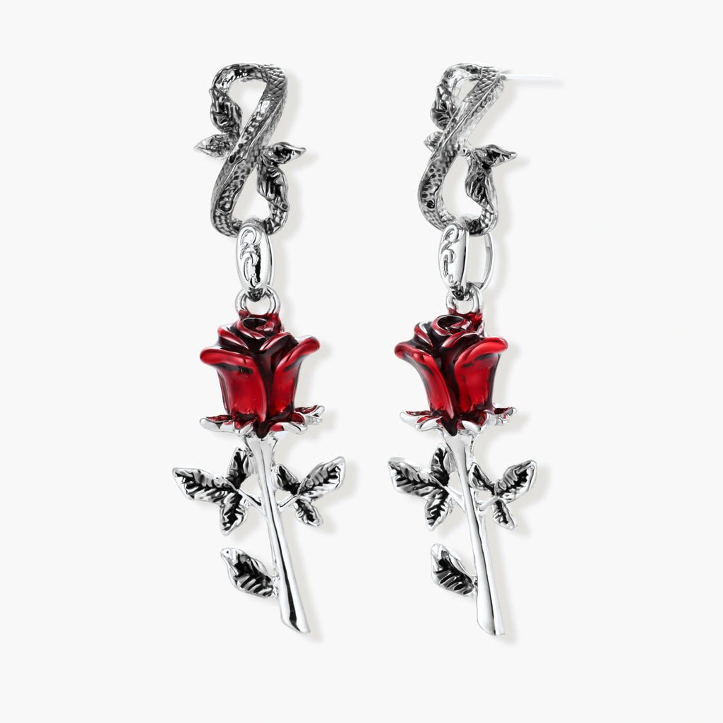 Gothic dangle earrings featuring silver serpent hooks with red enamel roses and metallic stems on white background.