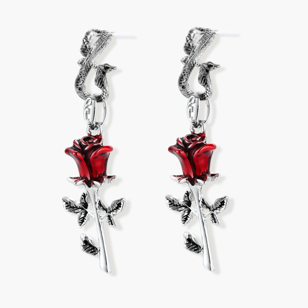 Gothic dangle earrings featuring silver serpent hooks with red enamel roses and metallic stems on white background.