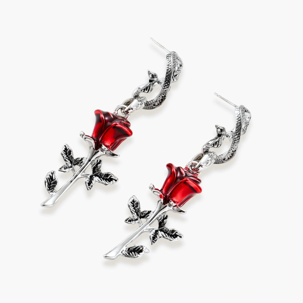 Gothic dangle earrings featuring silver serpent hooks with red enamel roses and metallic stems on white background.