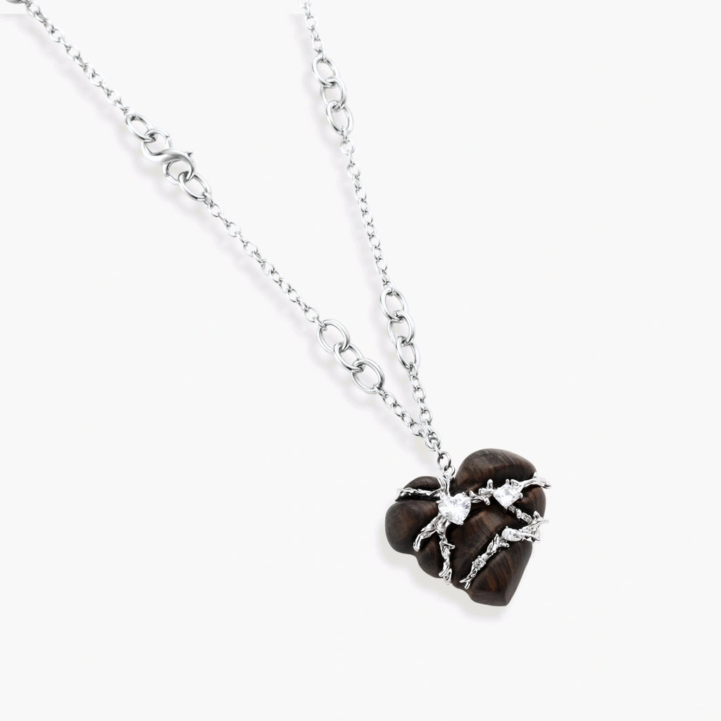 Dark ebony wood heart charms wrapped in intricate silver chains with crystal accents, shown as matching earrings and necklace set.