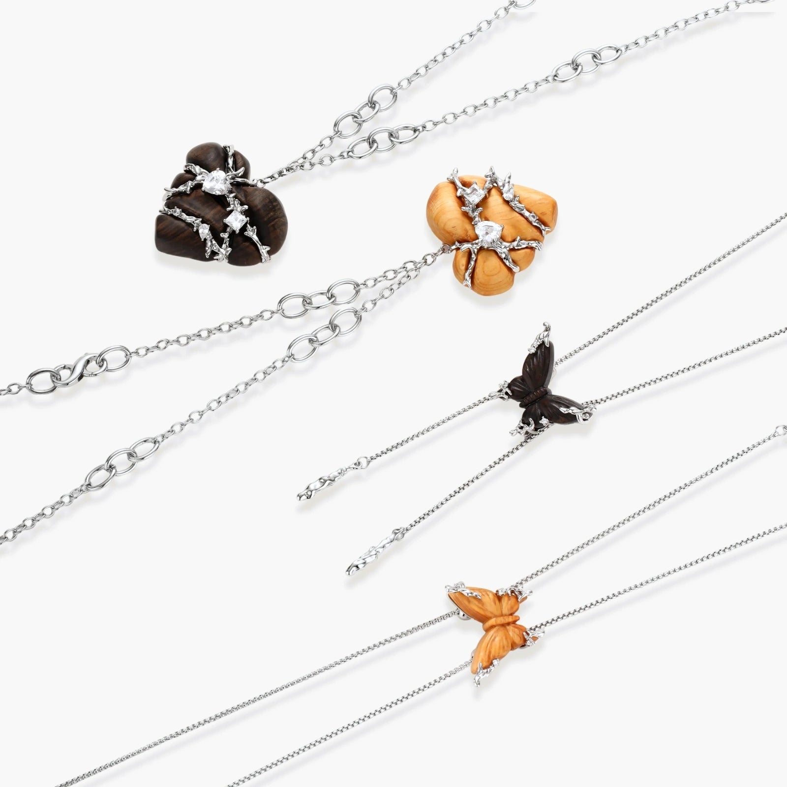 Dark ebony wood heart charms wrapped in intricate silver chains with crystal accents, shown as matching earrings and necklace set.