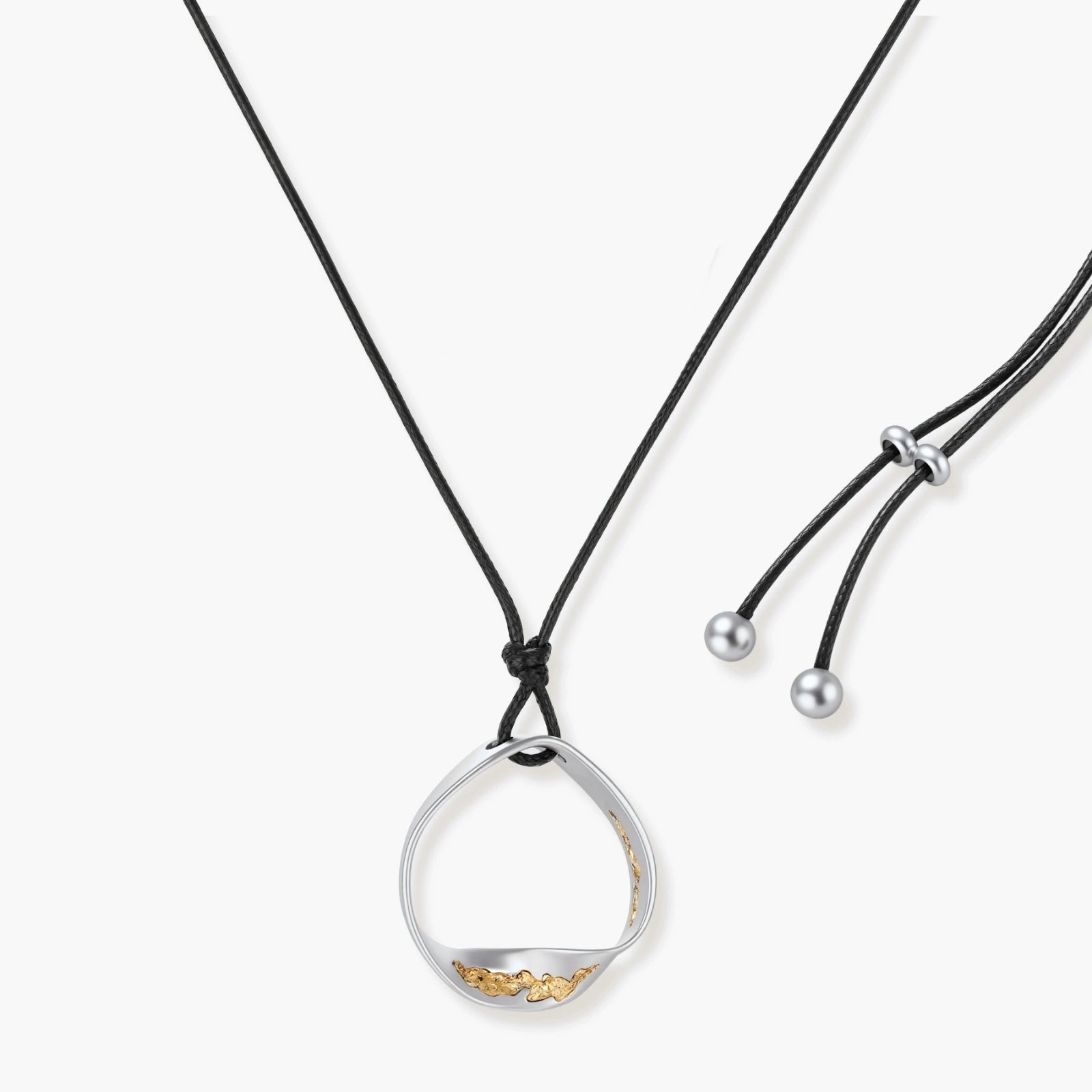 Artistic jewelry set featuring curved silver pendant with gold veining on black cord plus matching asymmetrical hoop earrings