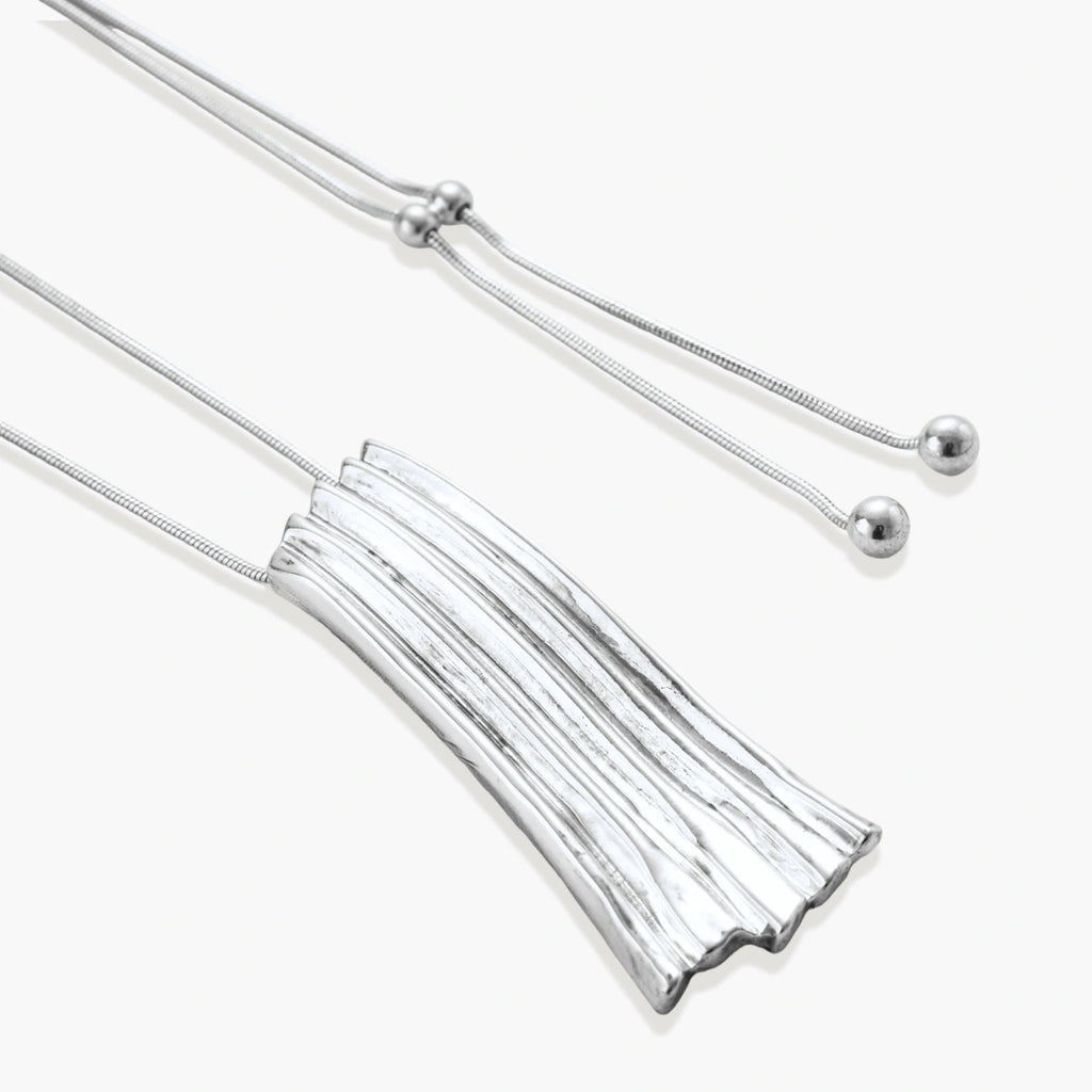 Layered metallic wing-shaped pendant and matching earrings with feathered texture in silver and gold finishes
