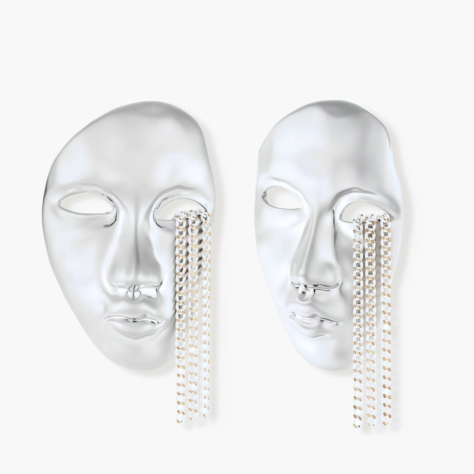 Silver face-shaped statement earrings with flowing chain tassels hanging from sculpted lips on cream background