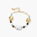 Gold-plated bracelet with baroque pearl centerpiece, turquoise and amber natural stones on adjustable chain against white background.