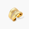 Adjustable gold-plated cuff ring with parallel ridged texture and diagonal row of sparkling zirconia stones on white background.
