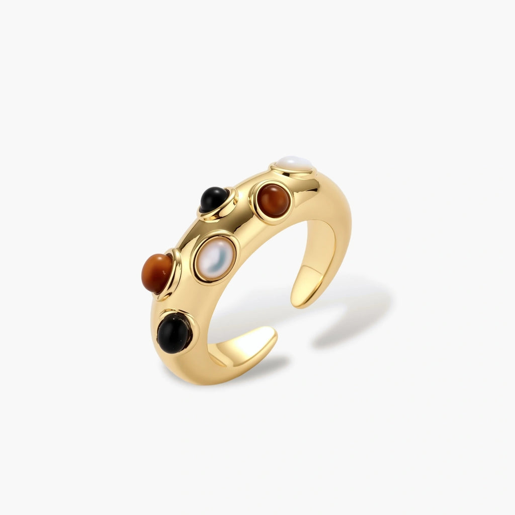 Gold-plated adjustable ring with white, amber, and black stones in organic bubble design on neutral background.